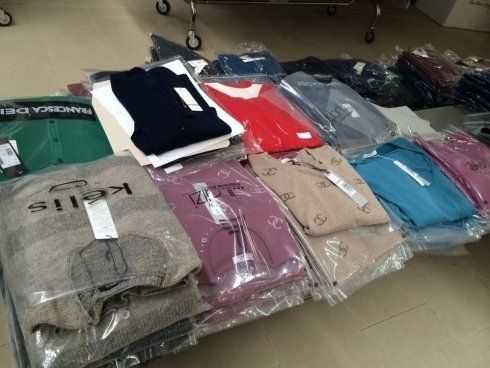 Mucchio di maglioni avvolti in vari colori, alcuni con etichetta, su una superficie, probabilmente destinati alla vendita al dettaglio.