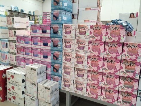 Scatole di biancheria intima impilate sugli scaffali di un negozio, con molti colori e fantasie visibili.