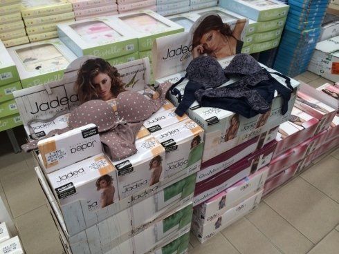 Esposizione di lingerie in un negozio, con reggiseni, biancheria intima e sagome di cartone promozionali.