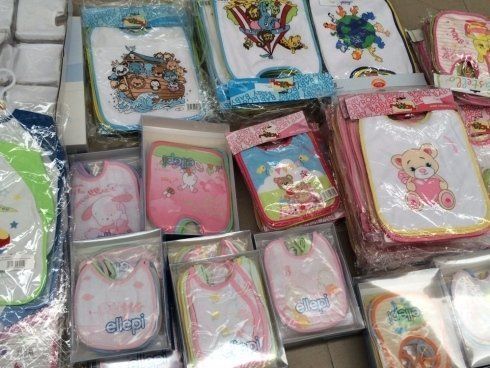 Bavaglini per bambini confezionati con disegni di cartoni animati, vari colori e fantasie in esposizione.