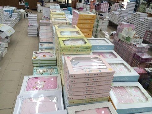 Scatoloni di biancheria per neonati in un negozio. Scatoloni rosa, gialli e verdi impilati in mostra.