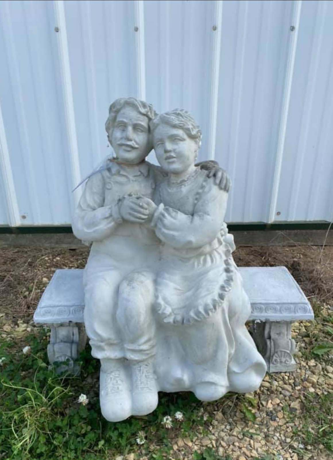 A statue of a man and a woman sitting on a bench.