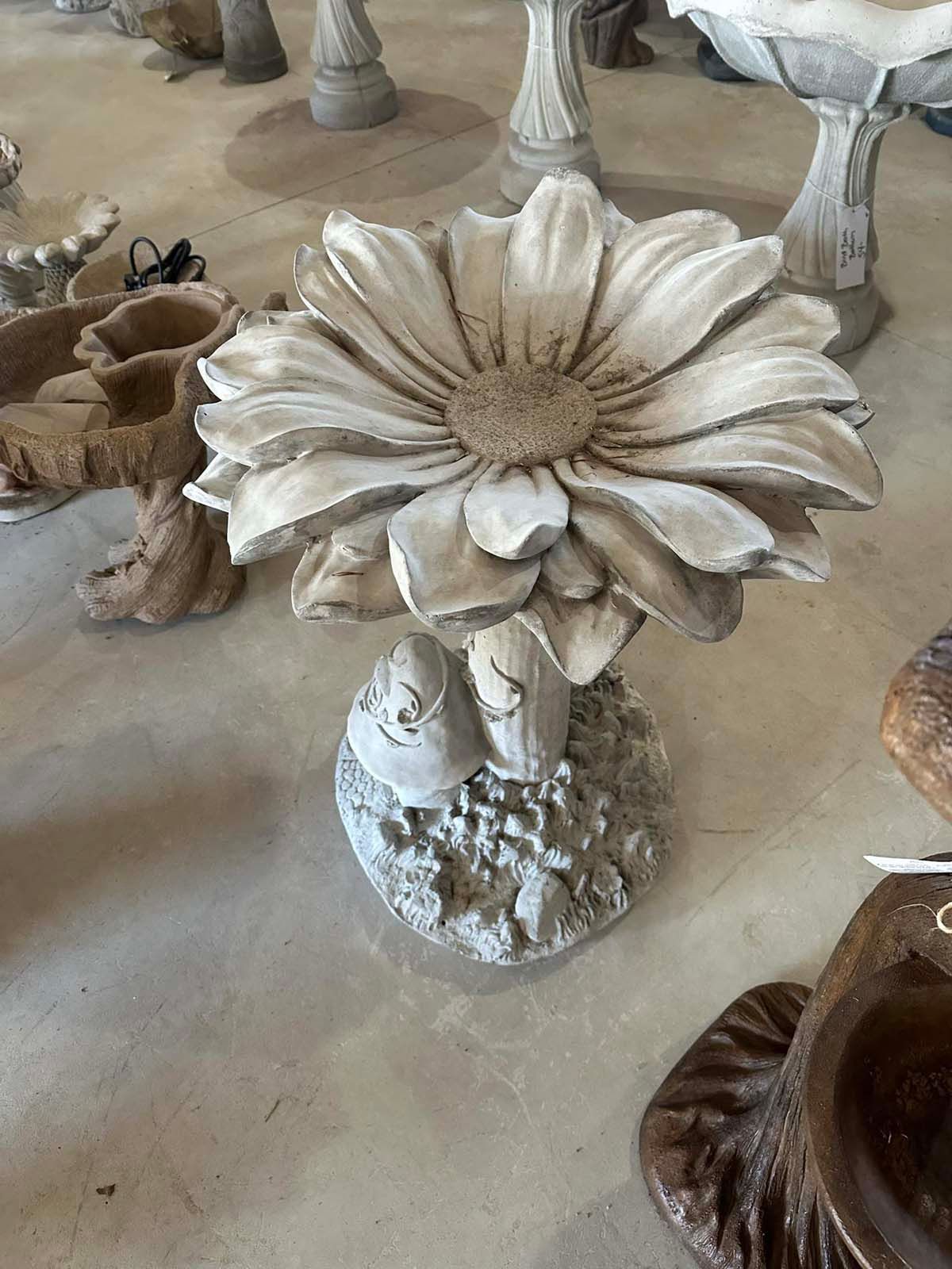 A bird bath in the shape of a flower is sitting on a table.