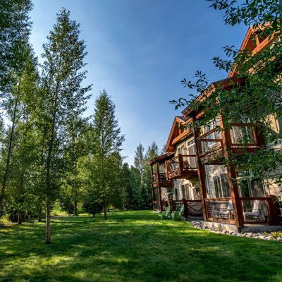 Lush green lawn and trees border a multi-story building with balconies, under a blue sky.