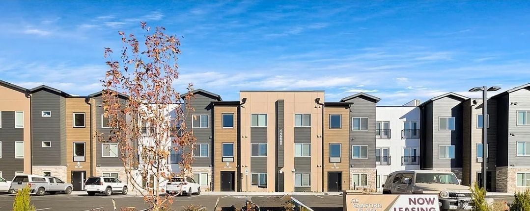 Modern townhouses with various colored facades under a blue sky.