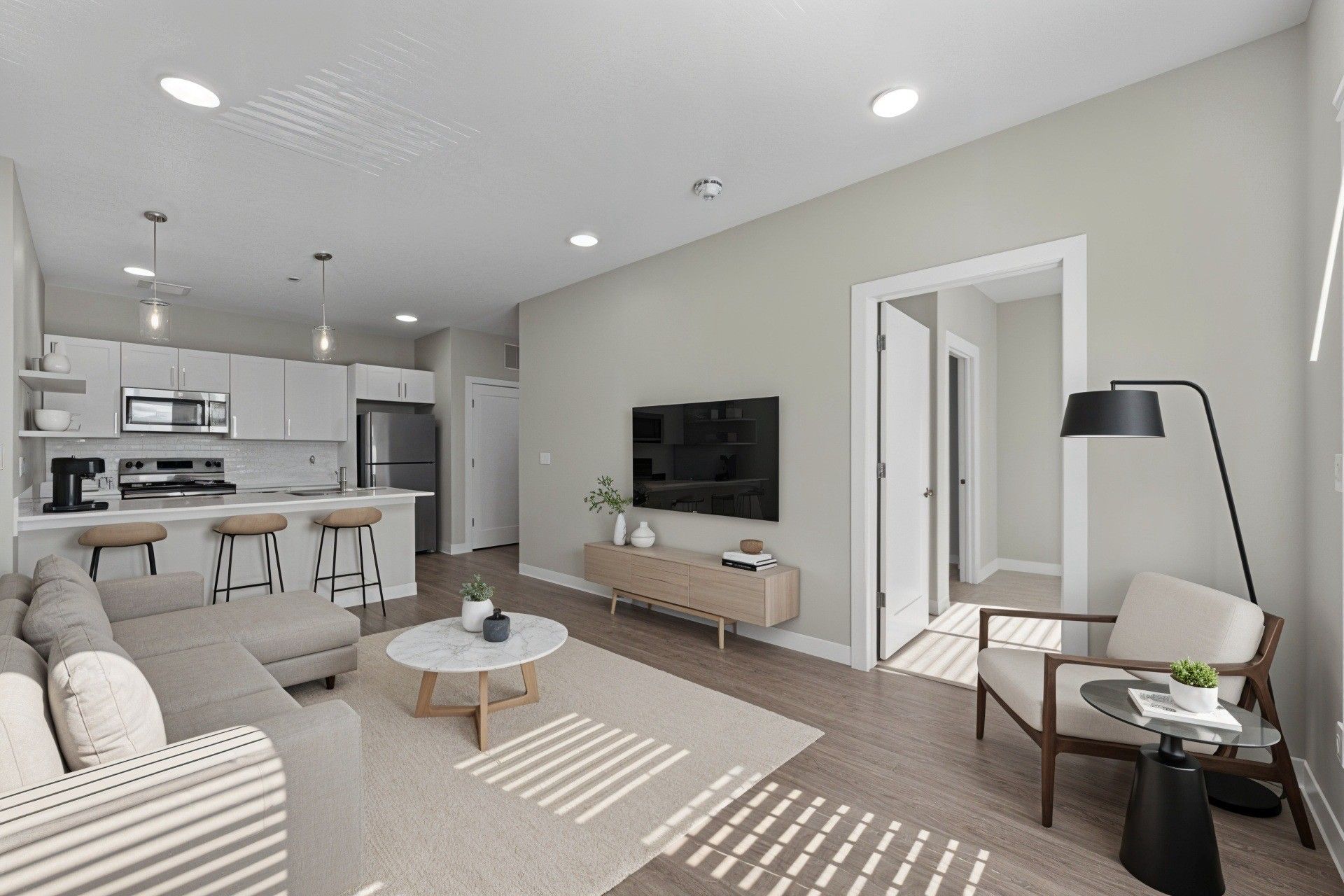 Modern living room with open kitchen, sectional sofa, TV, and neutral color scheme.