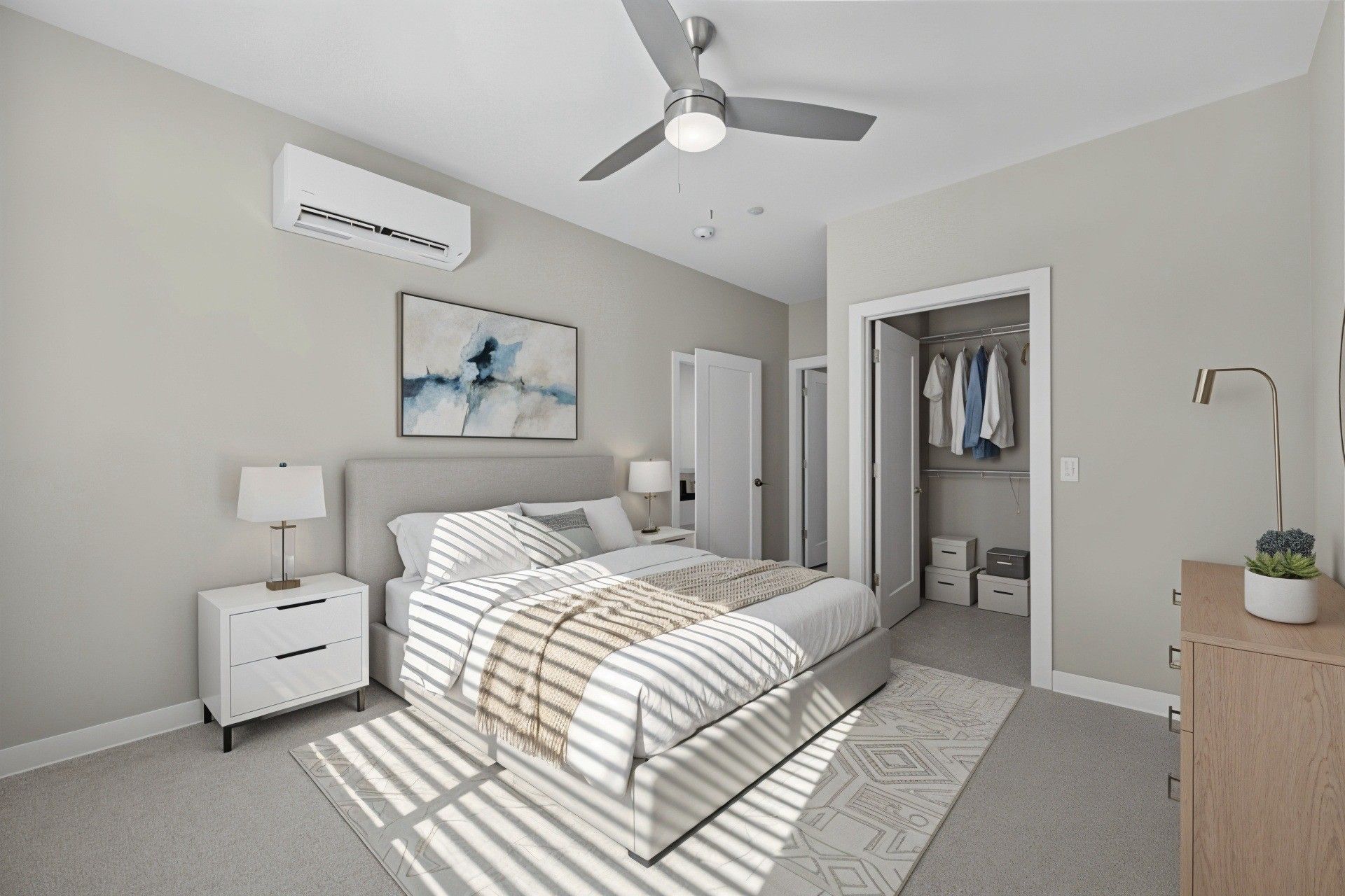 Bedroom with bed, closet, and air conditioner. Neutral tones with a rug, art, and bedside tables.