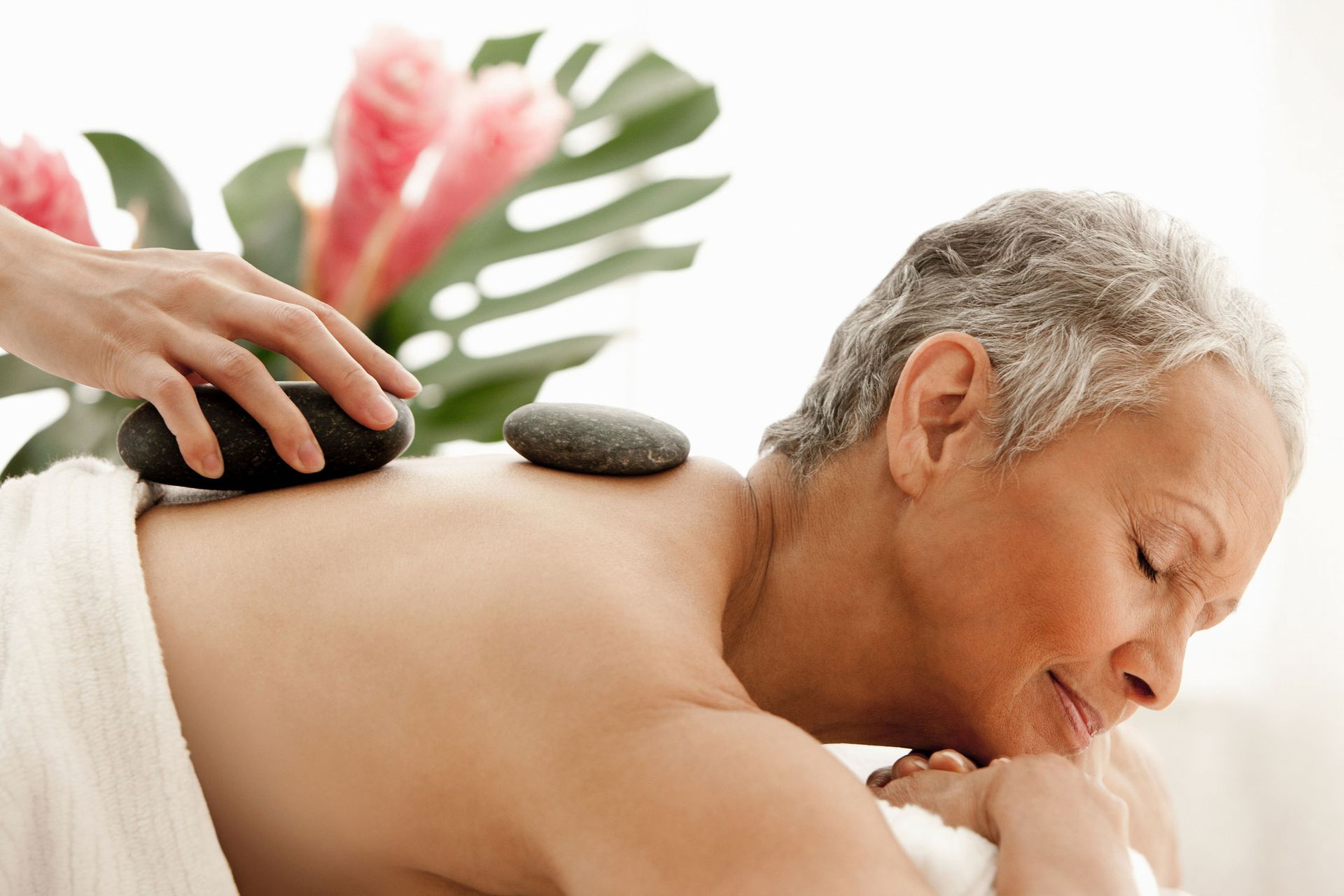An older woman is getting a hot stone massage at a spa.