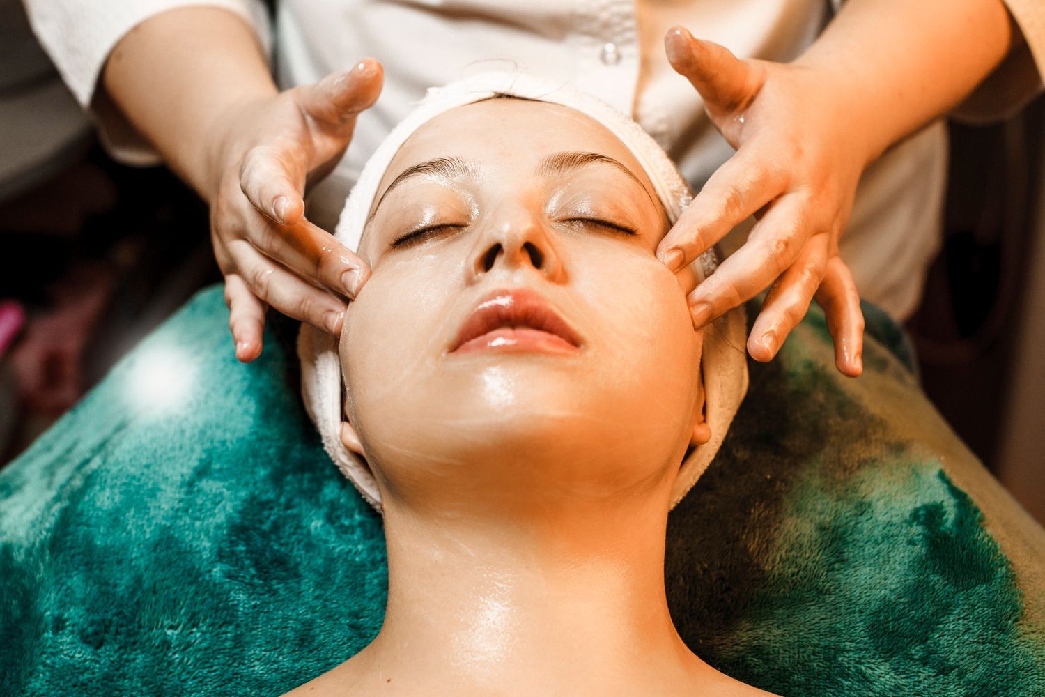 A woman is getting a facial massage at a spa.