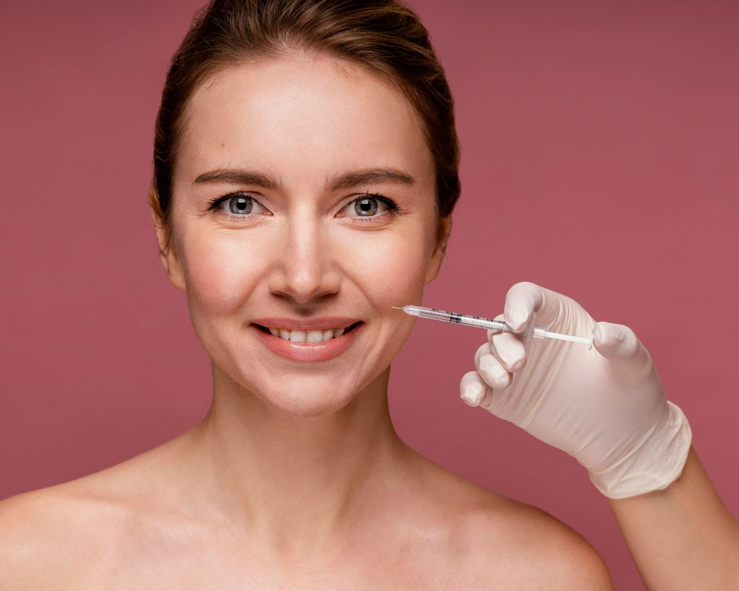 A woman is smiling while getting a botox injection in her face.