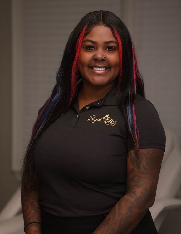 a woman with long red hair and a nose ring is smiling for the camera .