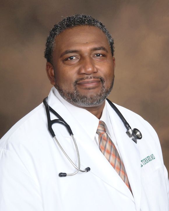 a man in a white coat and red tie smiles for the camera