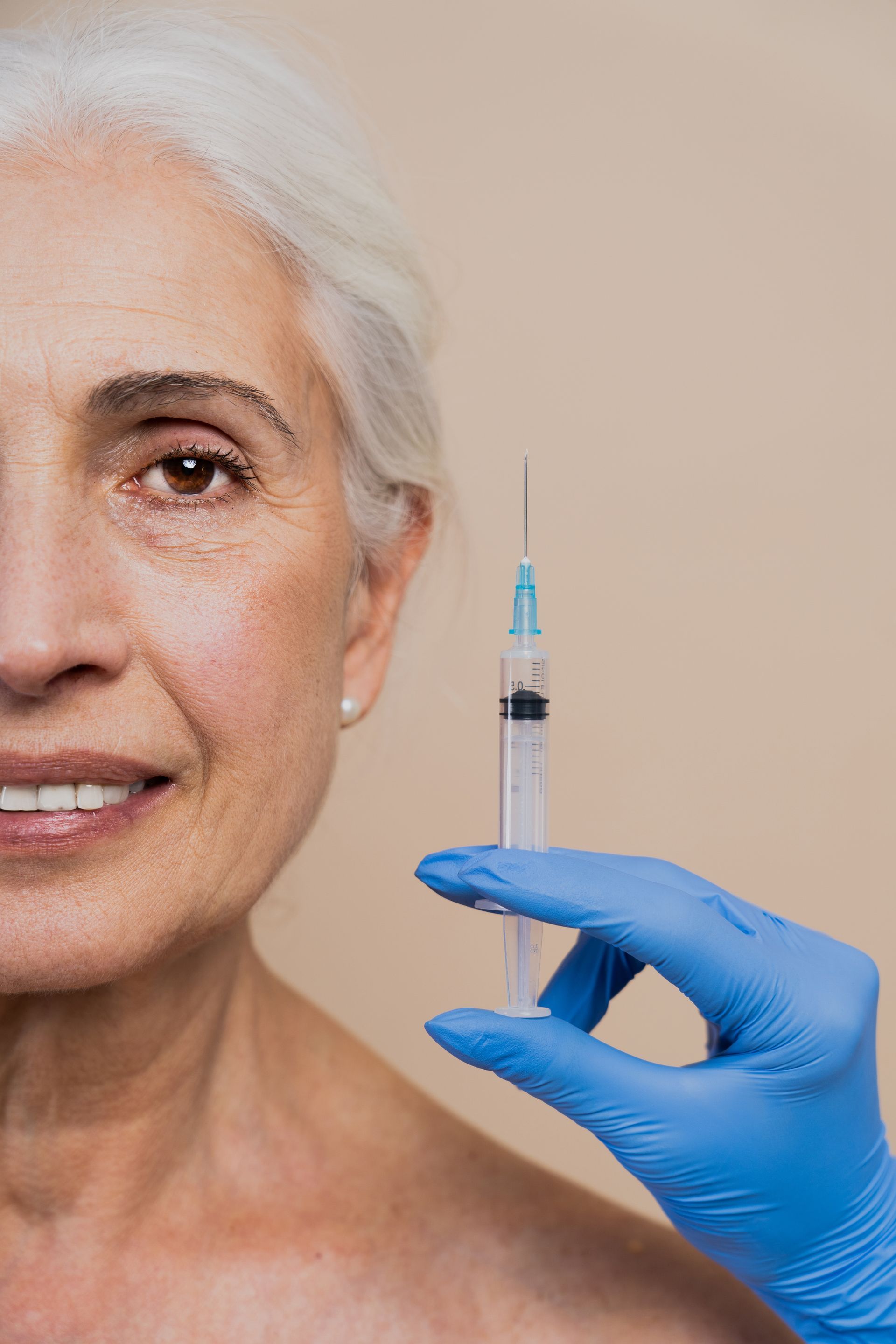 a woman is smiling while holding a syringe in front of her face