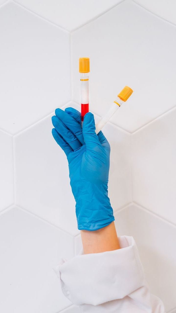 a person wearing blue gloves is holding a blood sample