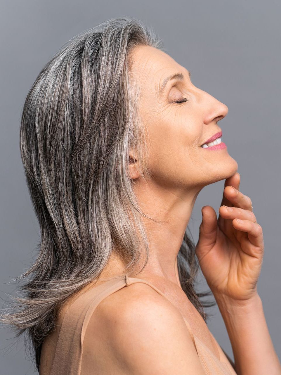 a woman with gray hair is smiling with her eyes closed