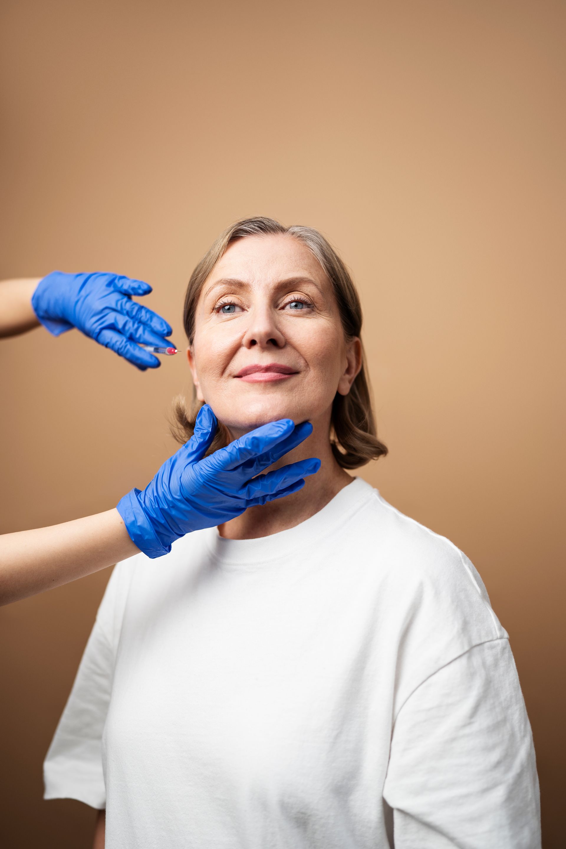 a woman in a white shirt is being examined by a doctor in blue gloves
