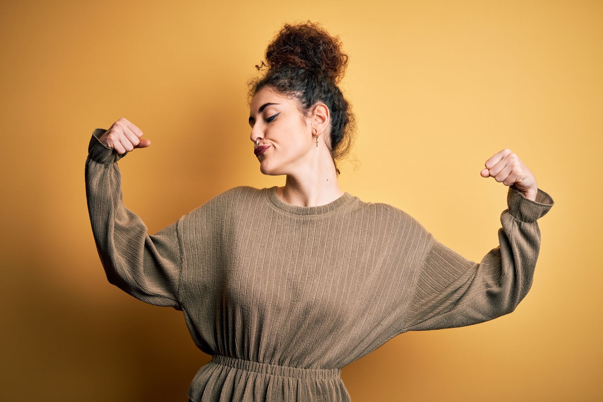 a woman in a brown sweater is flexing her muscles