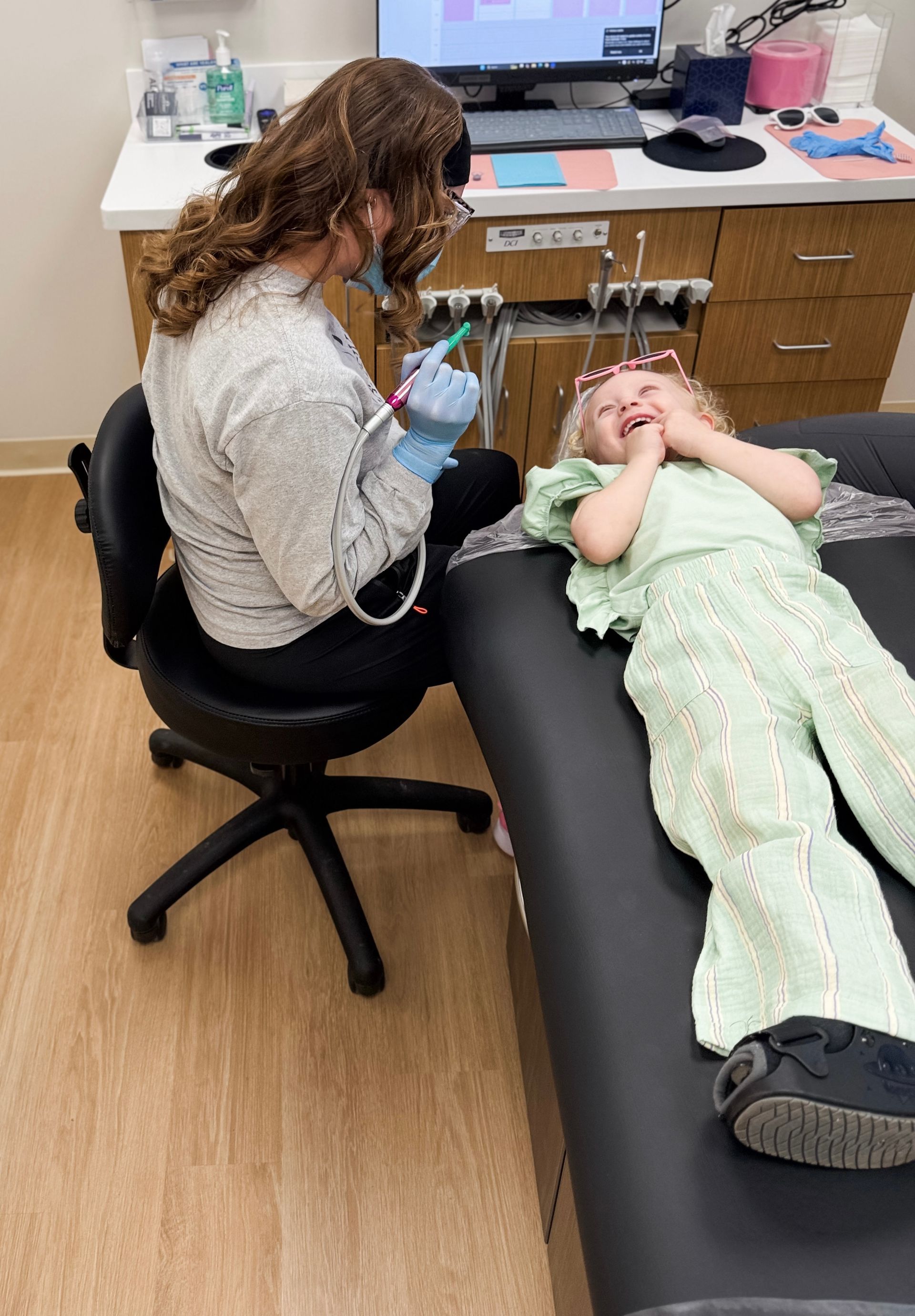 A young boy is sitting in a dental chair while a dentist examines his teeth.