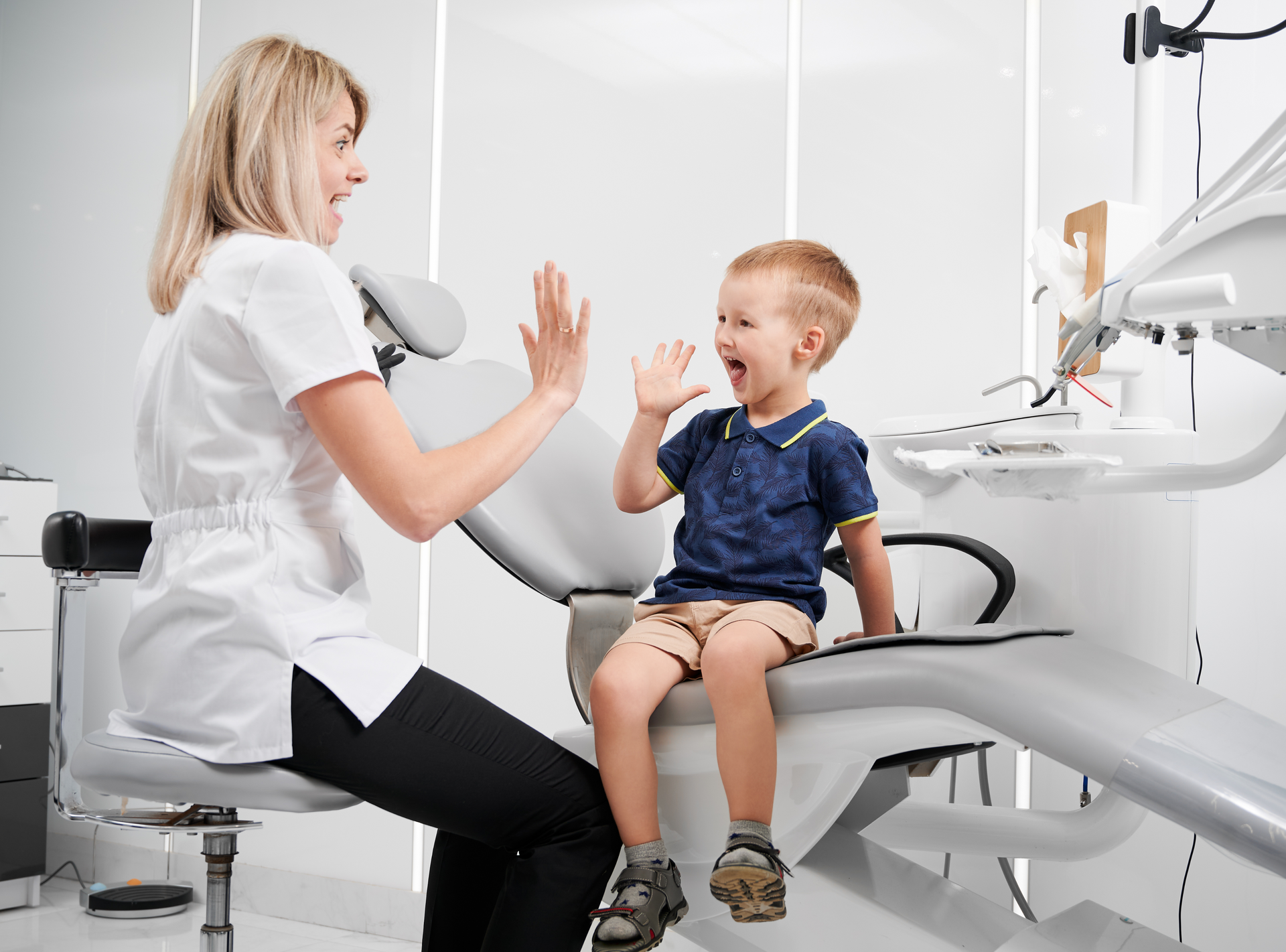 A woman is giving a child a high five in a dental office