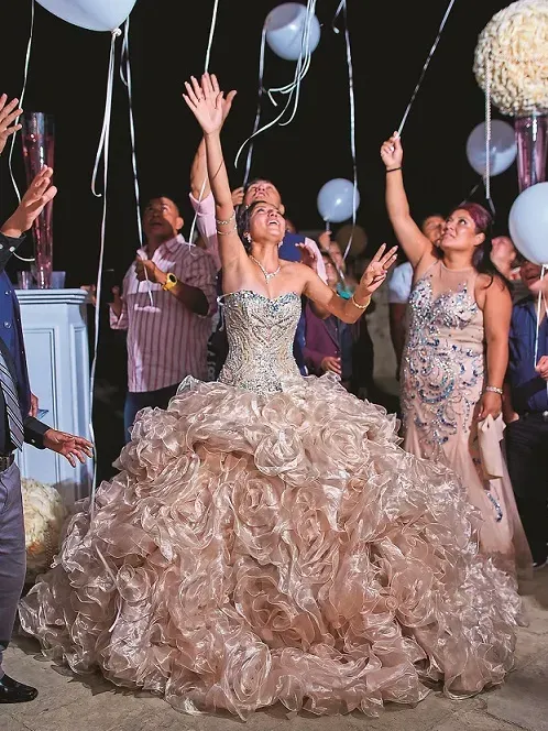 Woman in a gold ball gown celebrating with friends and balloons at a party
