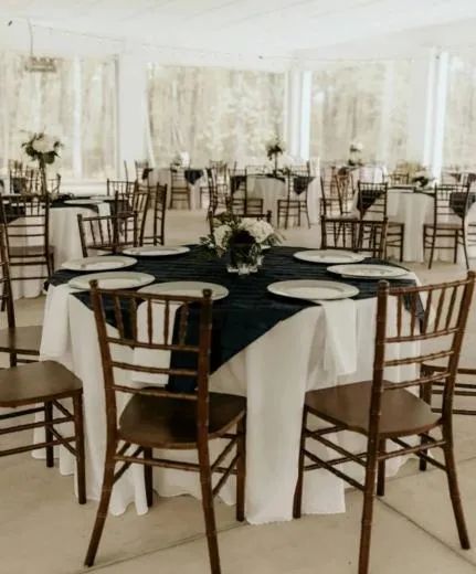 Elegant banquet hall with round tables, dark tablecloths, and wooden chairs arranged for a formal event