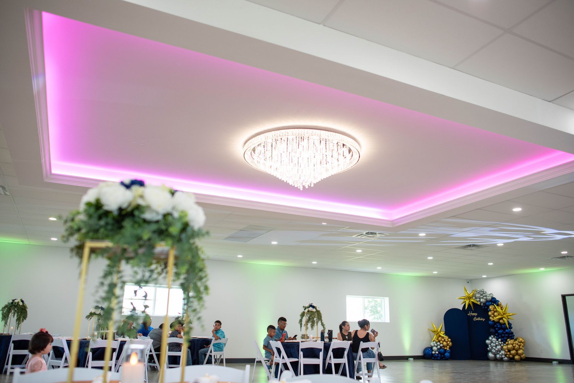 Elegant banquet hall with pink-lit ceiling, chandelier, and seated guests at tables