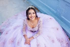 Smiling woman in a lavender ball gown sitting on a blue surface