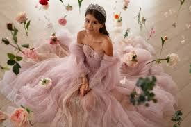 Young girl in a pink tulle gown posing among soft pink flowers and petals
