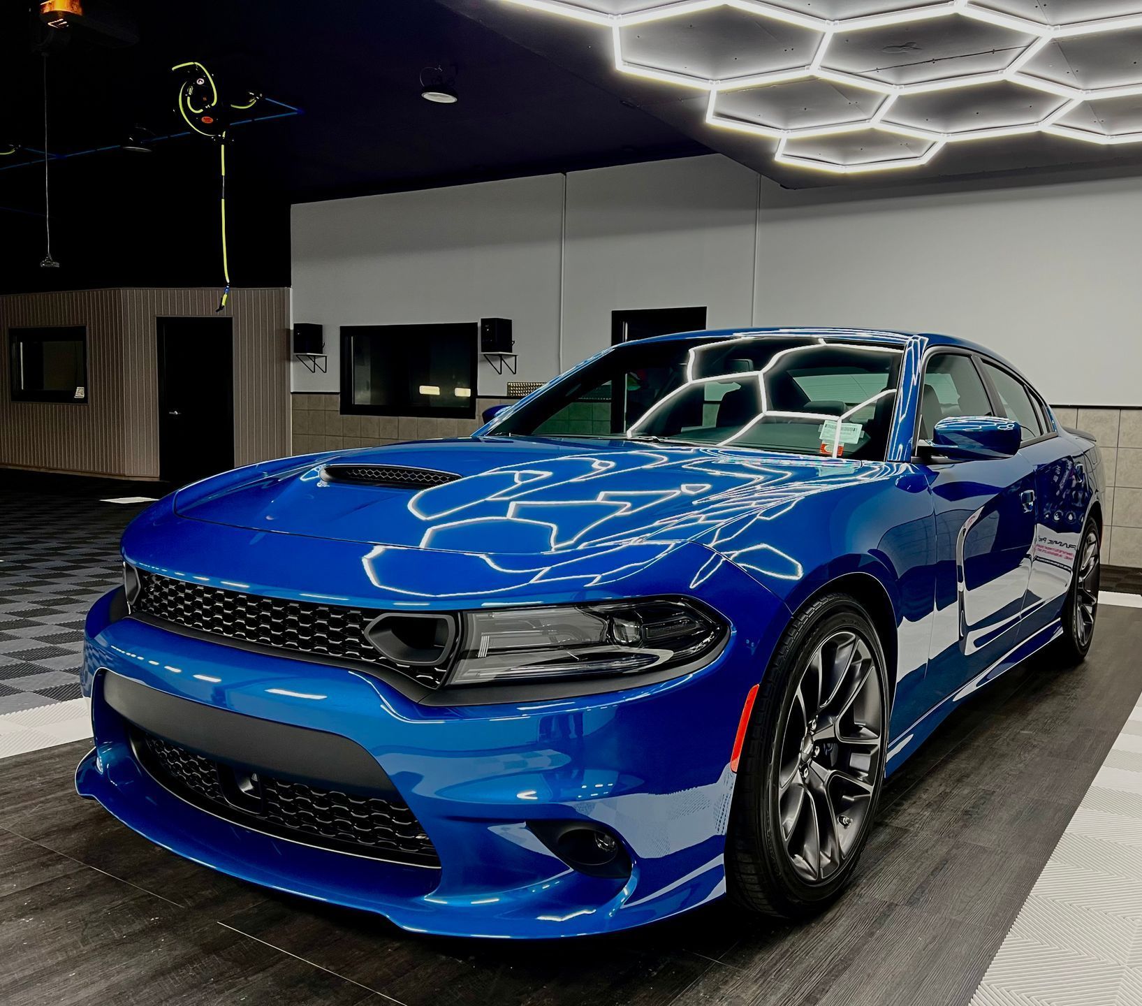 A blue dodge charger is parked in a garage.