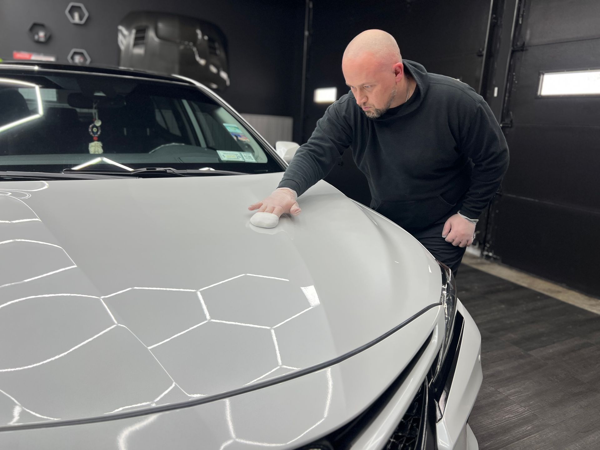 A man with a beard is cleaning the trunk of a car with a vacuum cleaner.