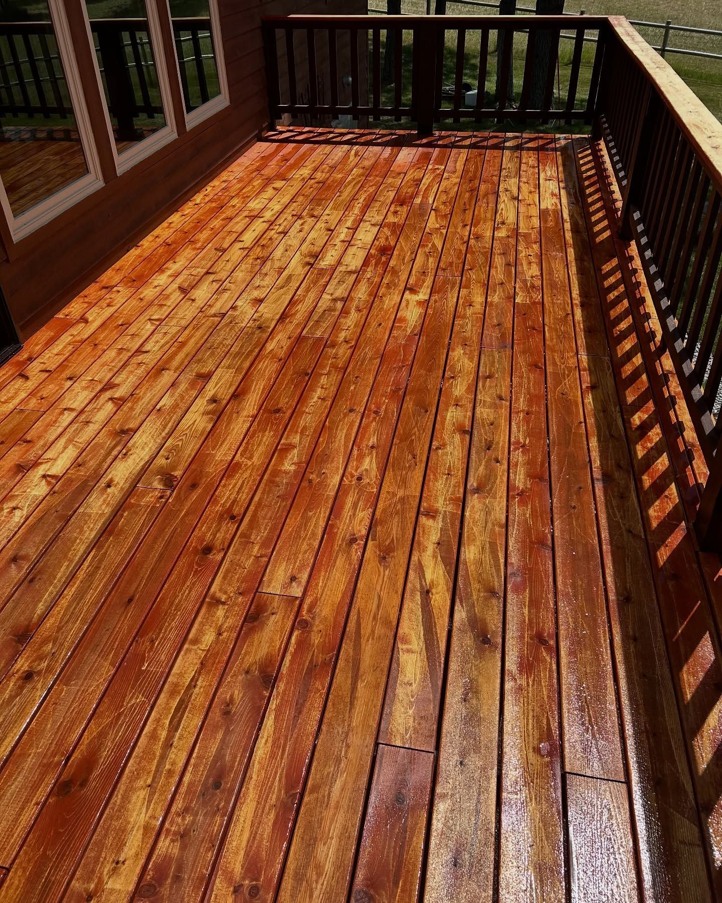 Woman in straw hat smiles, holding wine glass near a lake.