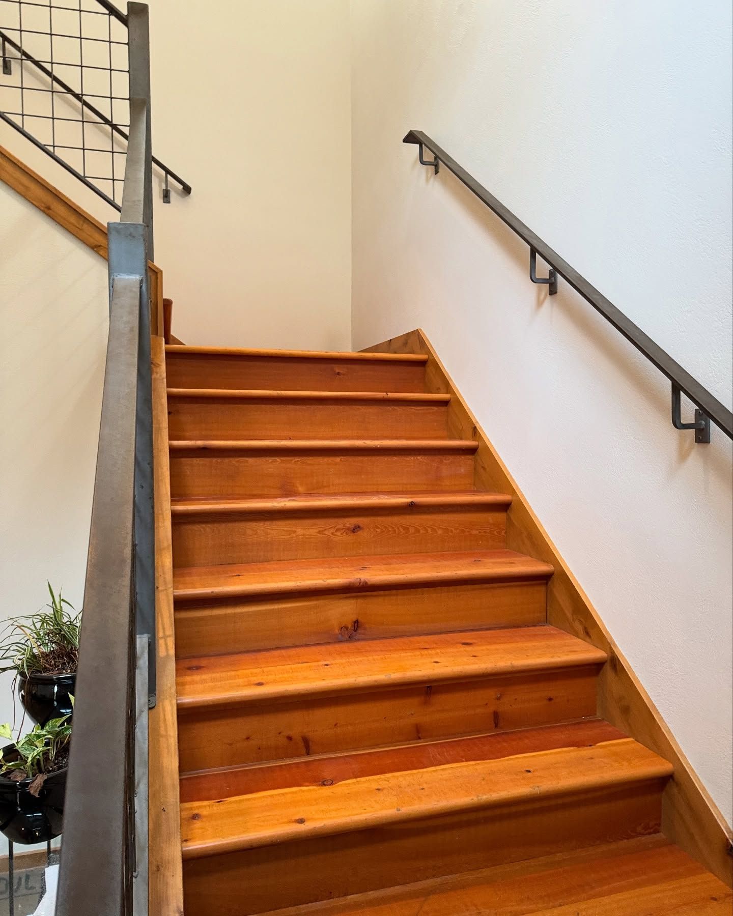 Woman in straw hat smiles, holding wine glass near a lake.
