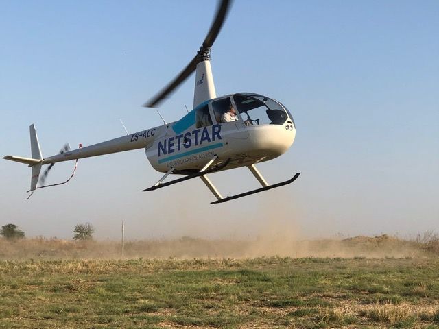 White Netstar helicopter landing somewhere in the bush in South Africa.