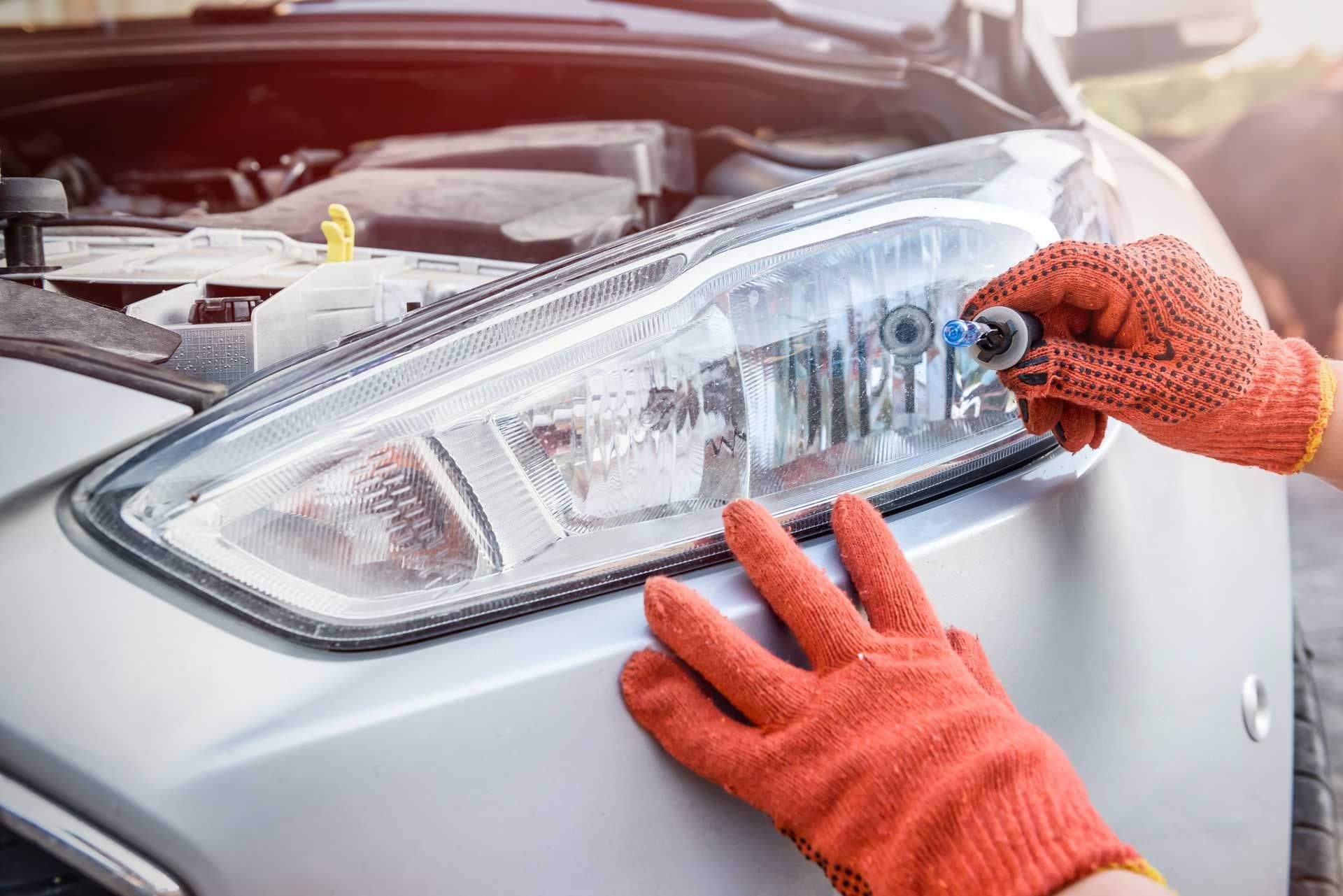 A person is fixing the headlight of a car.