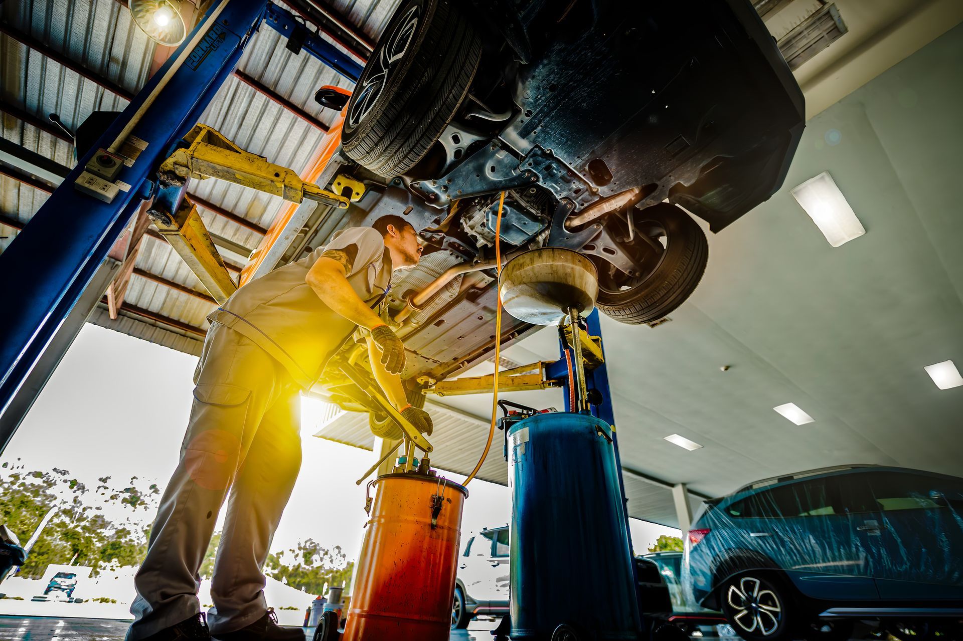 A man is working on the underside of a car in a garage.