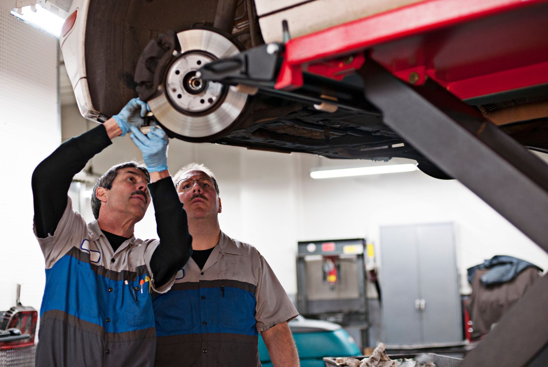 Two mechanics are working on a car in a garage.