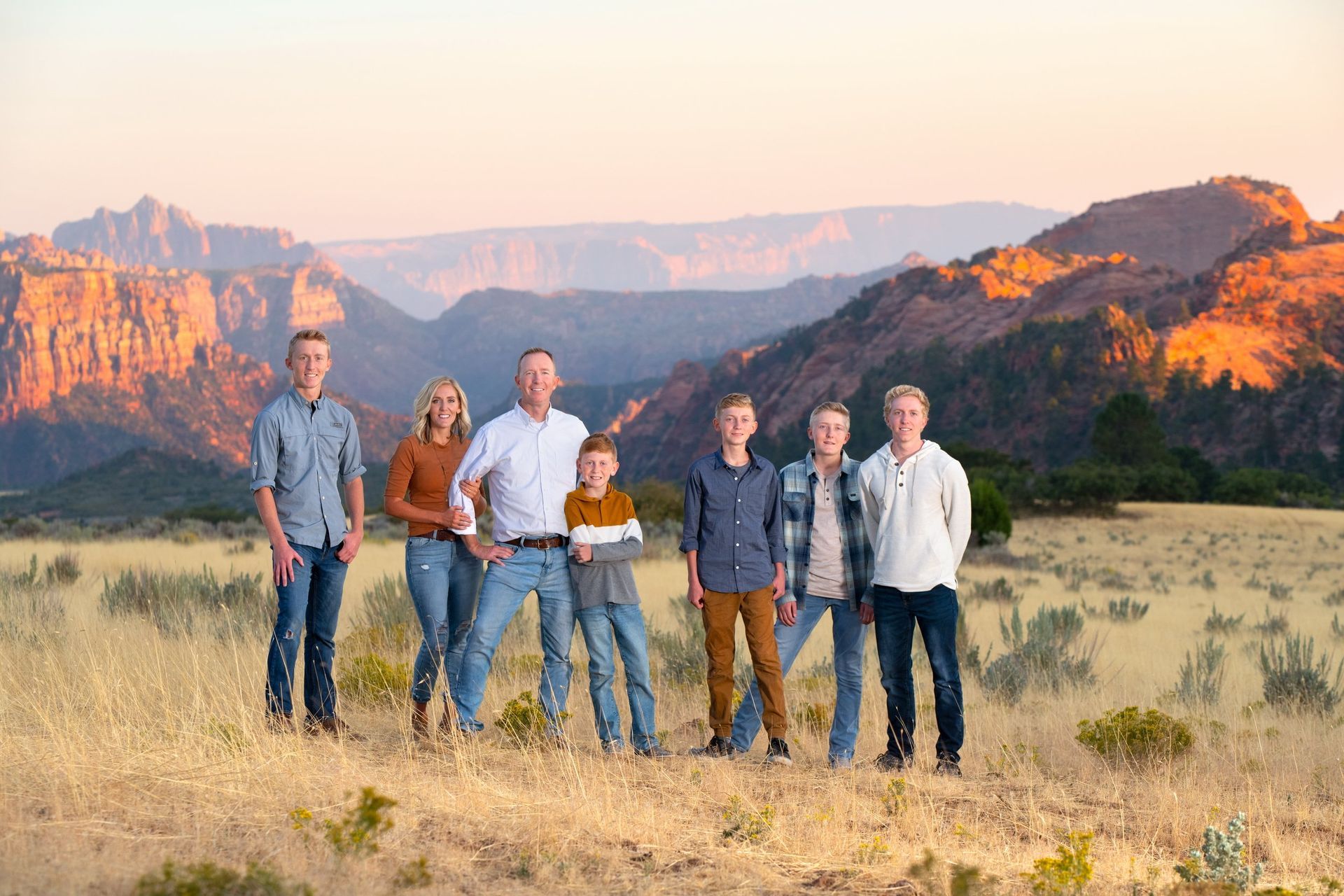 A family is standing in a field with mountains in the background.