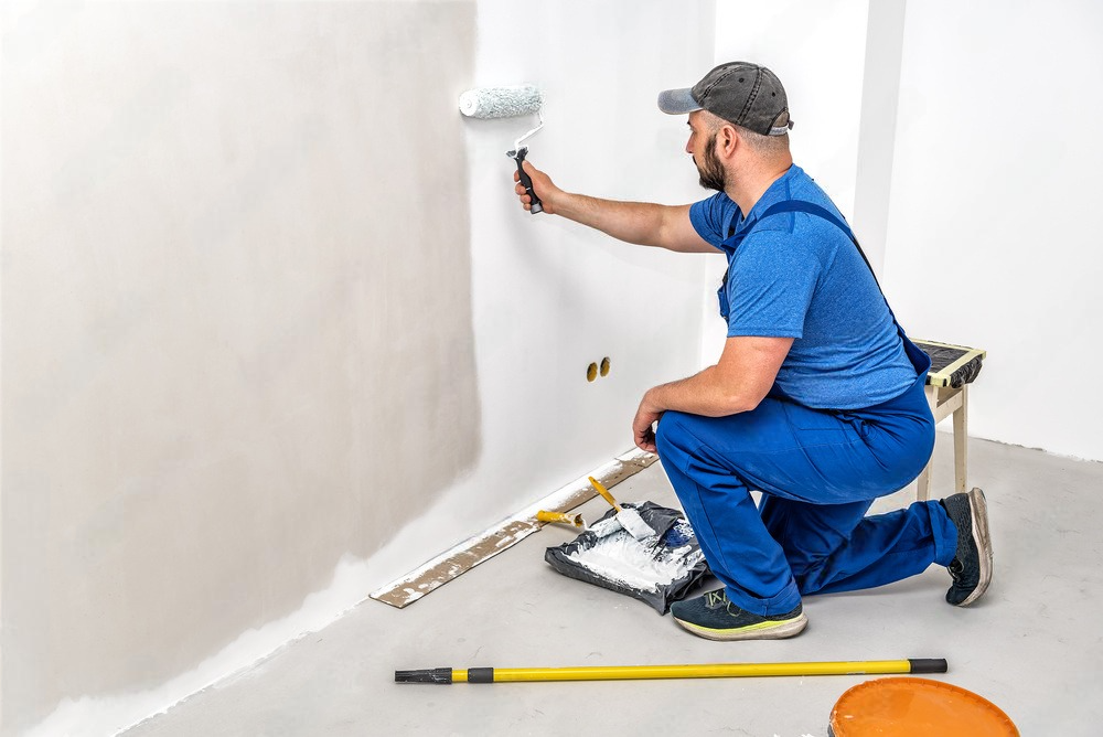 a man paints a wall with a paint roller