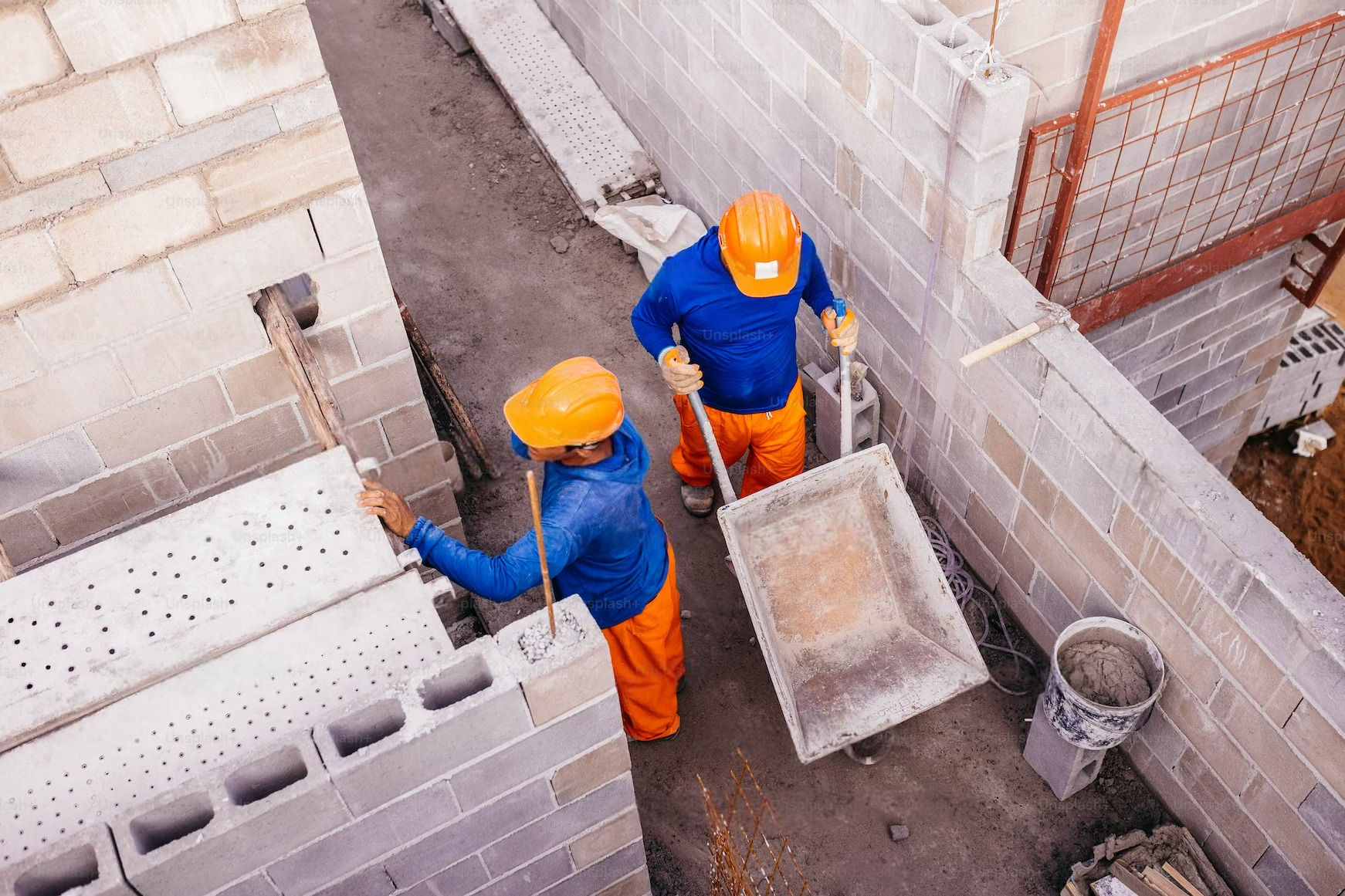 two construction workers are working on a brick wall .