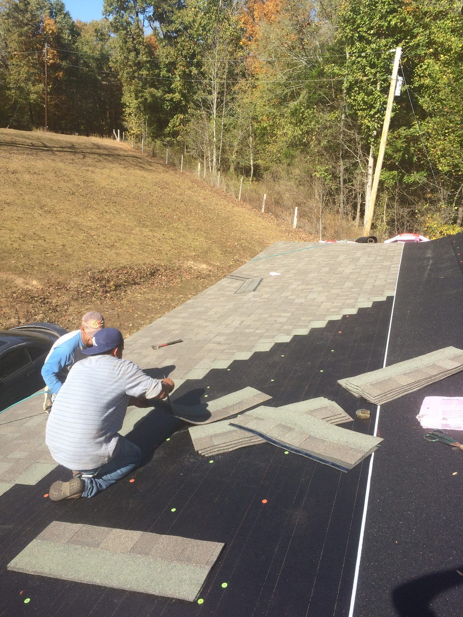 Two men are working on a roof in a field.