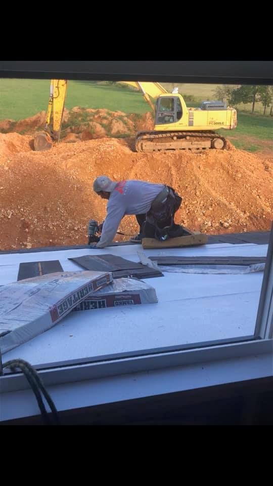 A man is kneeling on the ground in front of a construction site.
