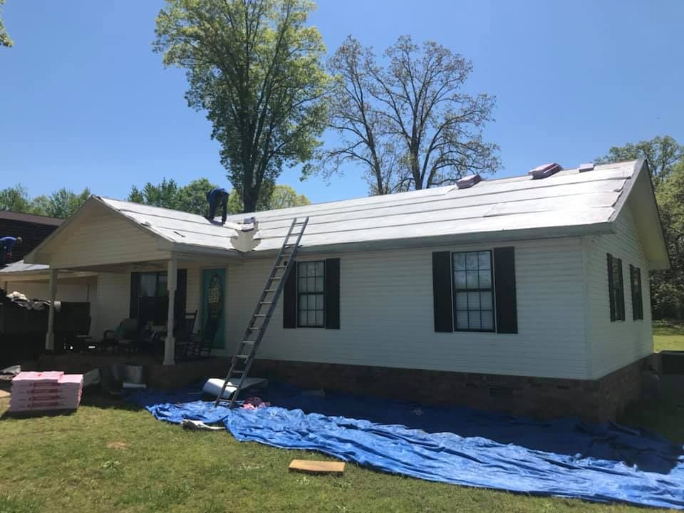 A white house with black shutters is being painted.
