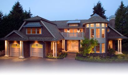 Luxury house with warm lights at dusk, featuring stone exterior, multiple gables, and a three-car garage