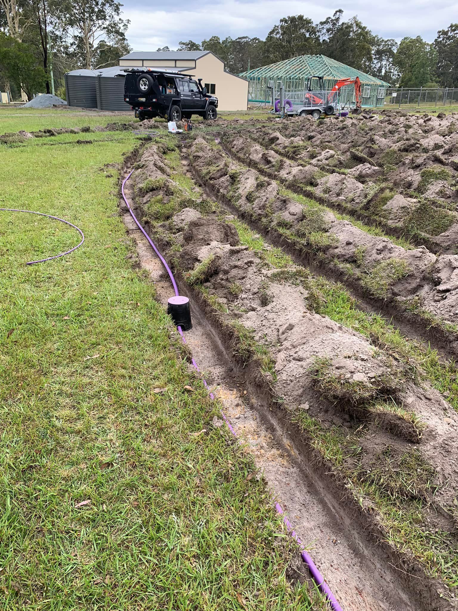 An irrigation system on a grassy field with a truck in the background — Matt King Plumbing & Septic Systems in Wauchope, NSW