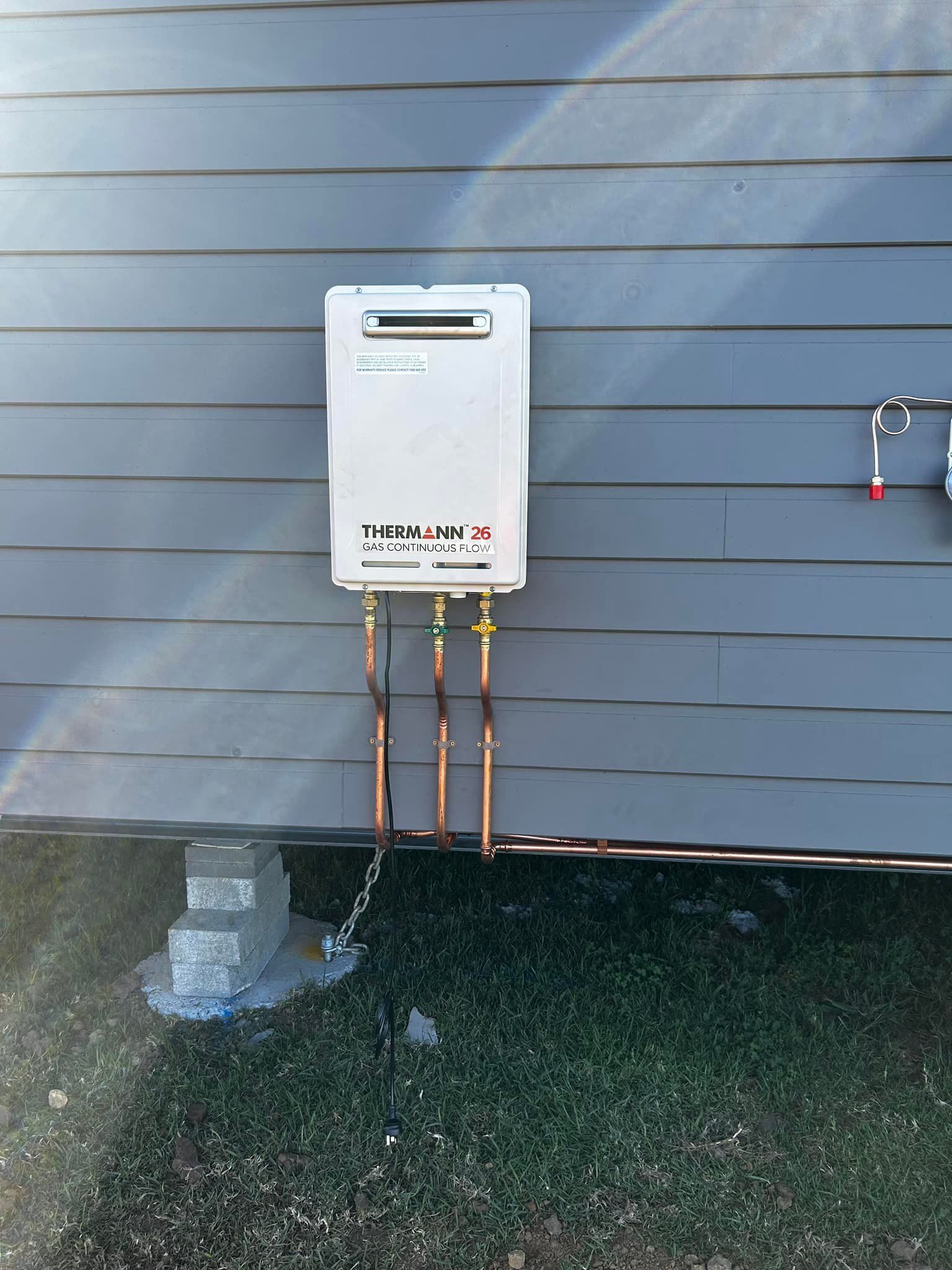 A therman water heater is attached to the side of a building — Matt King Plumbing & Septic Systems in Nabiac, NSW