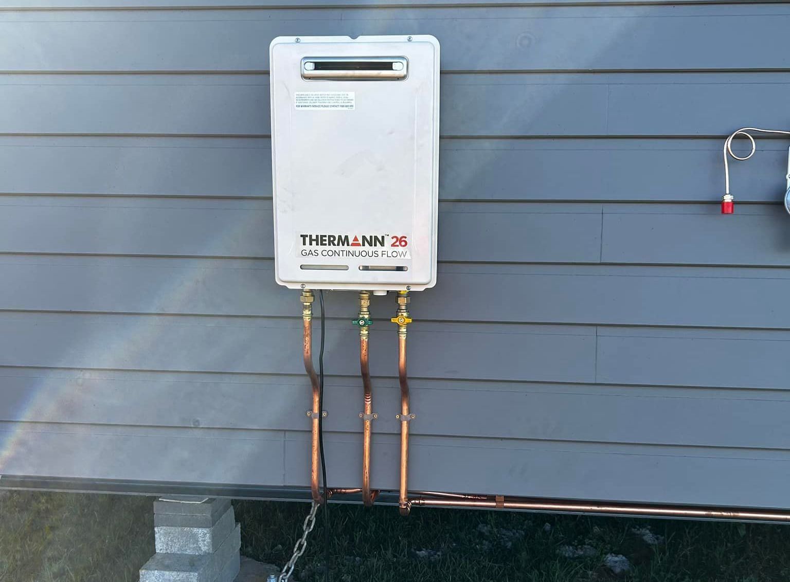 A therman water heater is attached to the side of a building — Matt King Plumbing & Septic Systems in Wauchope, NSW