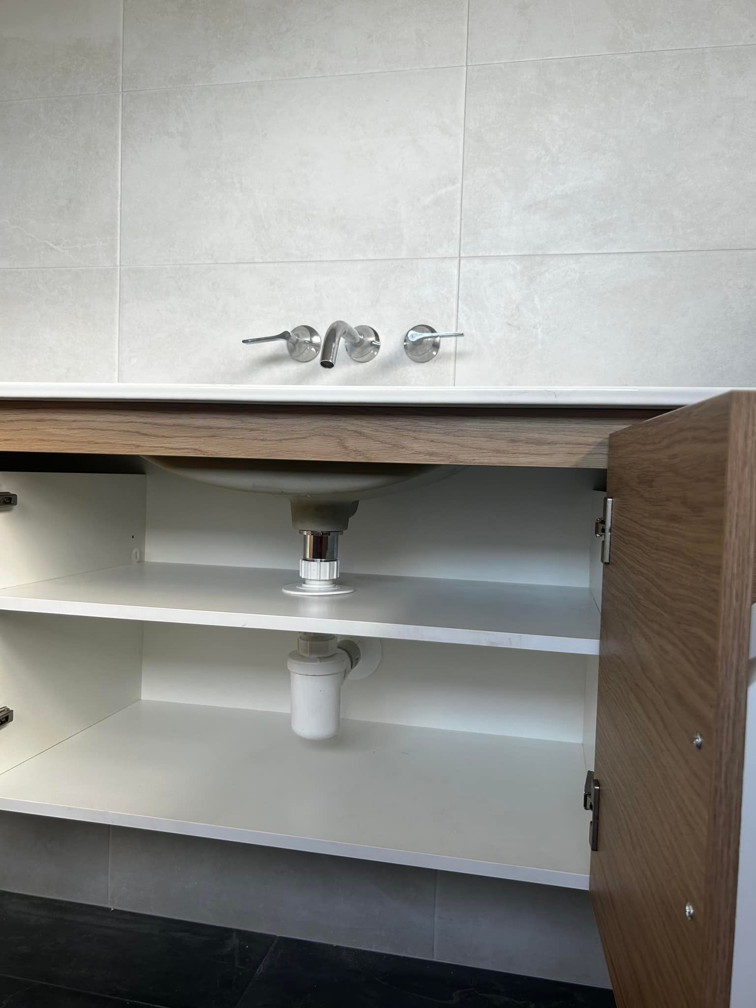 A bathroom vanity with the door open and a sink underneath it — Matt King Plumbing & Septic Systems in Taree, NSW