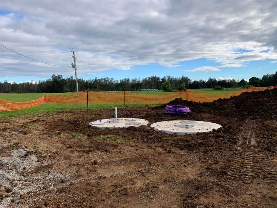 Two Septic Tanks Are Sitting in The Middle of A Dirt Field — Matt King Plumbing & Septic Systems in Taree, NSW