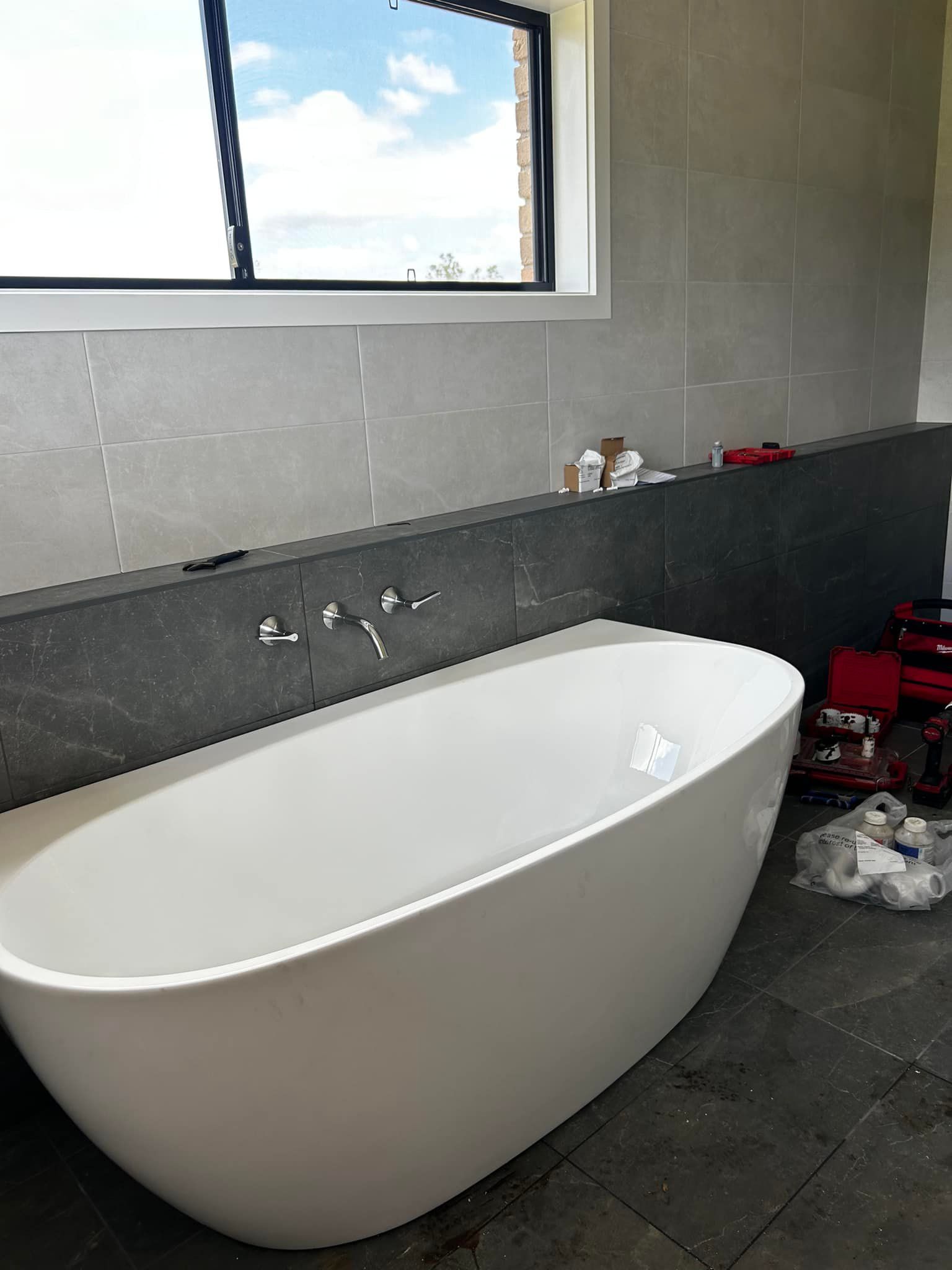 A white bathtub in a bathroom next to a window — Matt King Plumbing & Septic Systems in Old Bar, NSW