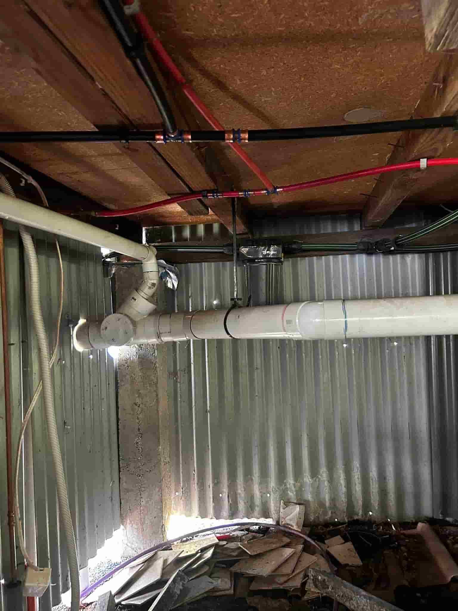 A Basement with A Lot of Pipes and Wires Hanging from The Ceiling — Matt King Plumbing & Septic Systems in Wauchope, NSW